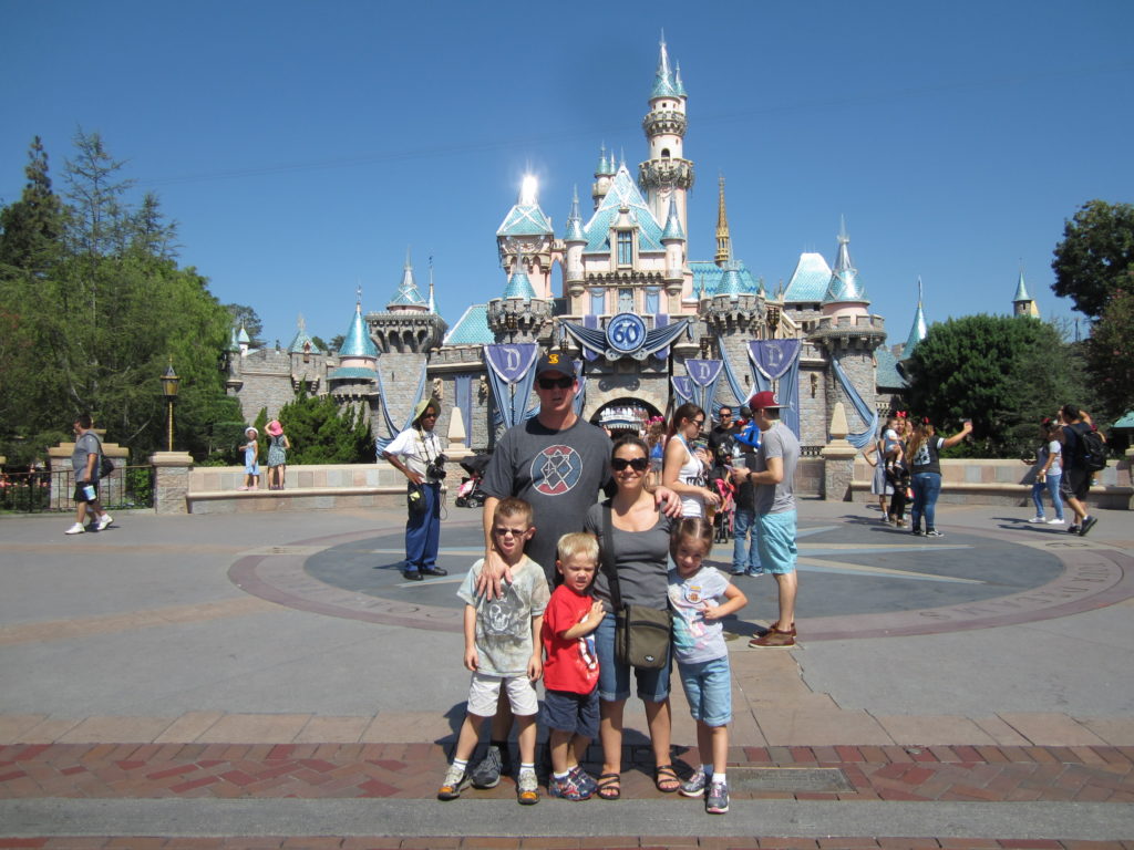 Family posing in front of castle at Disneyland.
