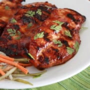 Vietnamese Grilled Chicken Breasts on a plate topped with fresh herbs.