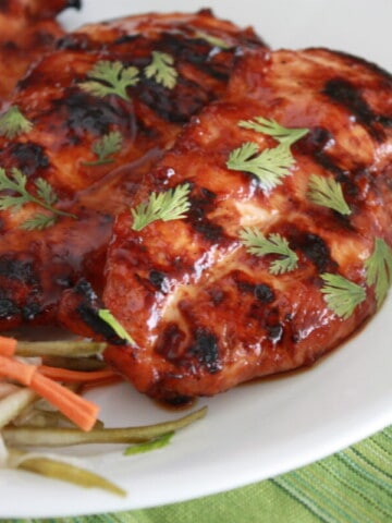 Vietnamese Grilled Chicken Breasts on a plate topped with fresh herbs.
