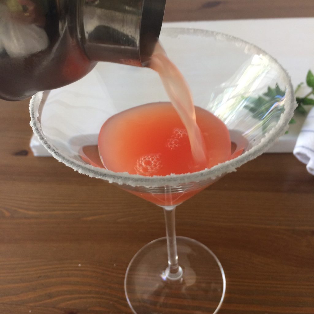 Watermelon Mint cocktail being poured from the shaker into the sugar-rimmed martini glass.