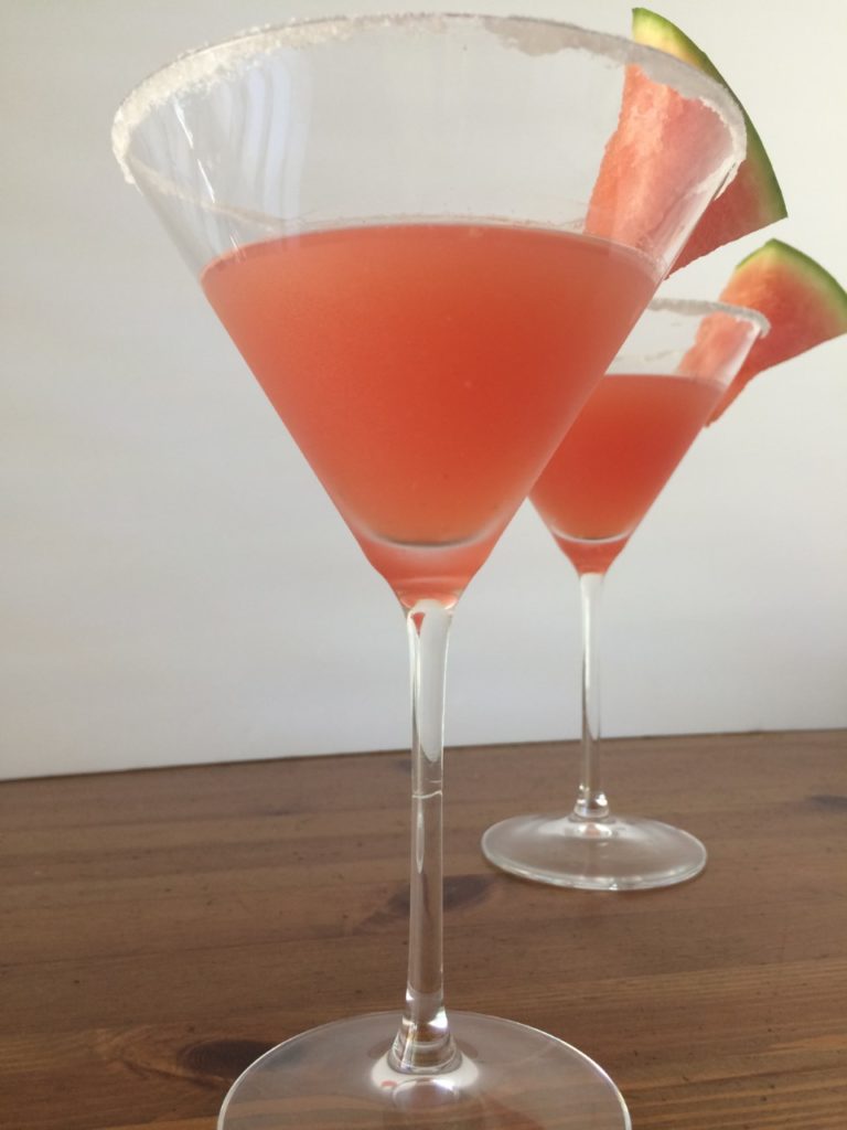 Watermelon mint martini in two glasses ready to sip & garnished with small wedges of watermelon.