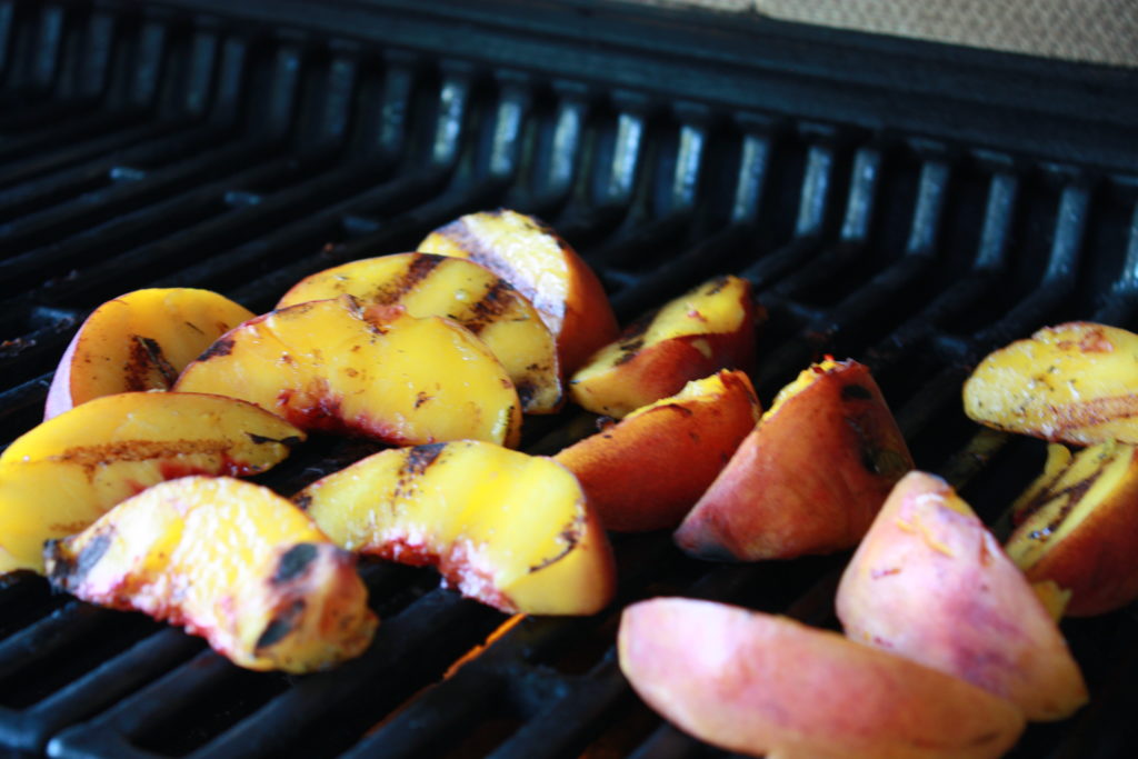 Peach halves cooking on the grill.