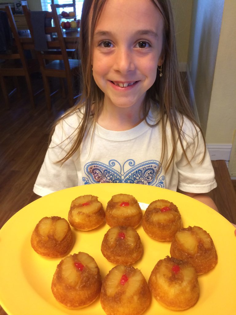 Young girl holding a plate with homemade desserts.