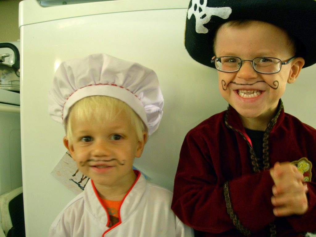 Two boys dressed in chef outfits ready to cook together as a family & learn the benefits.