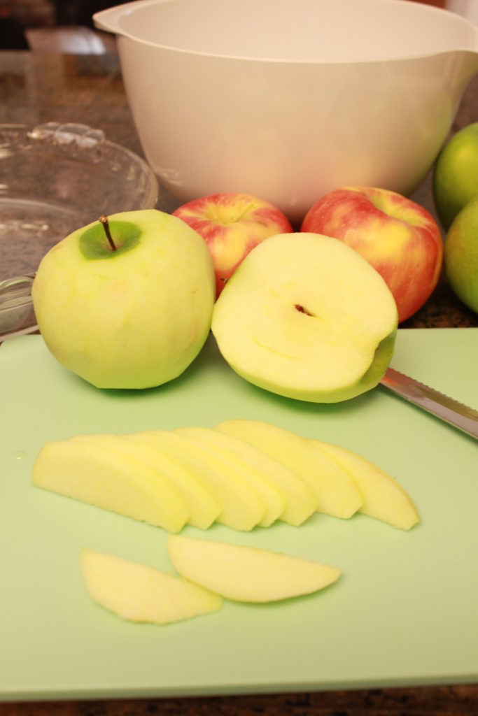 Thin sliced apples on a cutting board.