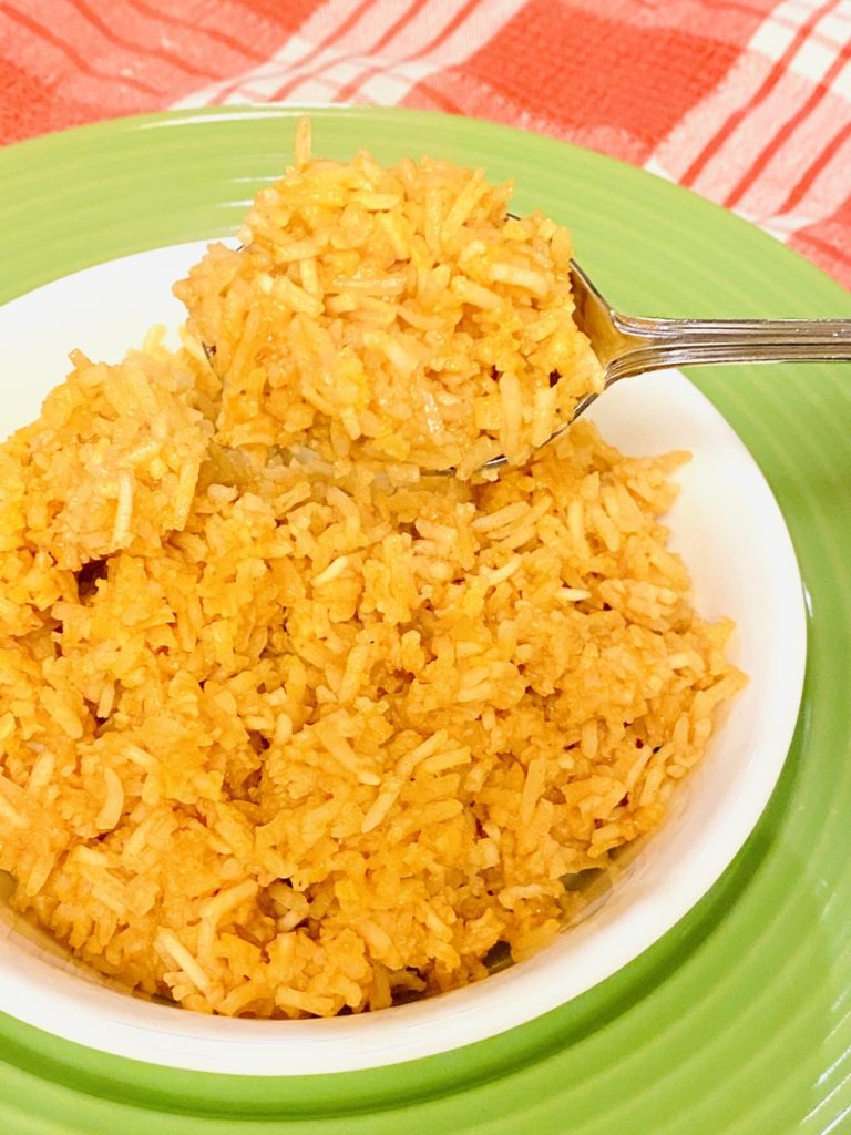 Easy Restaurant Style Mexican Rice in a bowl with a serving spoon.
