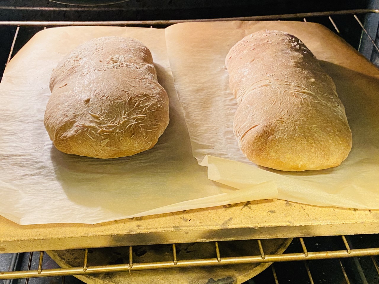 two loaves of ciabatta baking on a stone in the oven.
