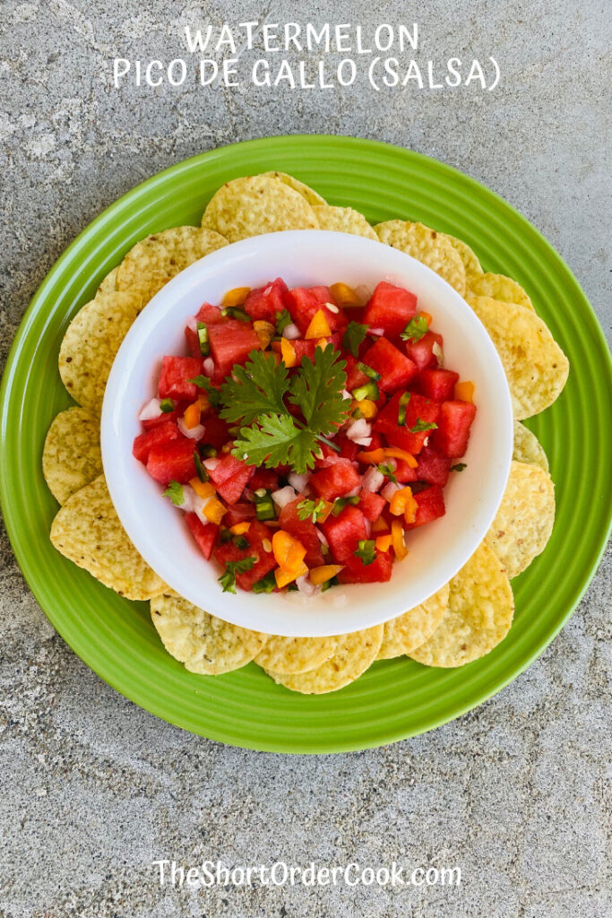 watermelon salsa with onions and peppers in a bowl on top of a plate circled with tortilla chip.s