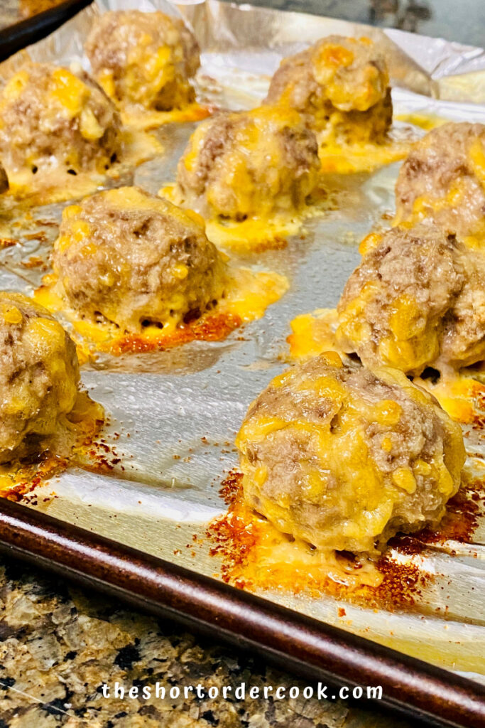 Keto Sausage Balls cooked on a baking sheet with cheese oozing out. 