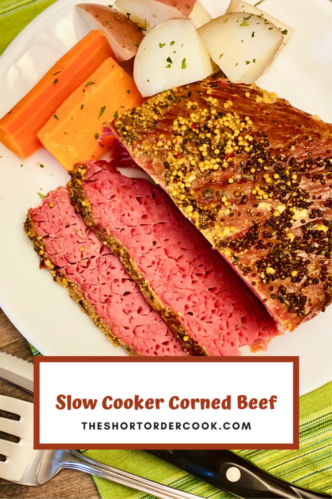 Slow Cooker Corned Beef on cutting board with carrots and potatoes