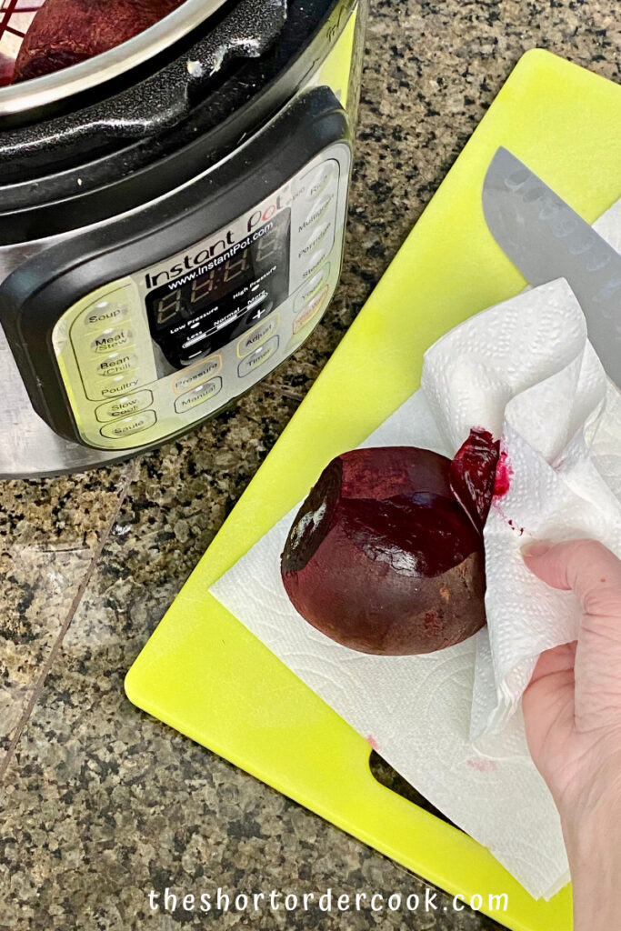 Instant Pot Steamed Whole Beets rubbing off the skin with a papertowel