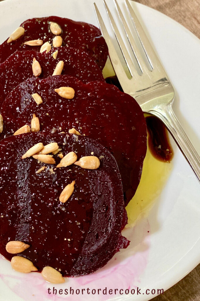 Instant Pot Steamed Whole Beets sliced on a plate with salt pepper, sunflower seeds, and dressing