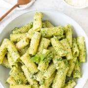 What to Serve with Lobster Pesto-Pasta-With-Homemade-Pesto-Sauce-3 healthylifetrainer overhead photo of a large bowl of rigatoni with bright green pesto plus a napkin and serving fork to the side and a small bowl of parmesan