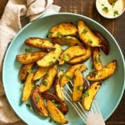 What to Serve with Lobster Small-Batch-Pan-Fried-Potato-Wedges-photo-9937 chocolatemoosey an overhead photo of a frying pan full of ready to eat wedge potato fries that are golden and sprinkled with parsley