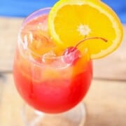 What to Serve with Lobster hurricane-drink-2-700x1050 bakingbeauty a glass full of hurricane cocktail with bright red and orange layered colored liquids and topped with a maraschino cherry and a slice of orange