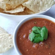What to Serve with Quesadillas Roasted-Tomato-and-Green-Onion-Salsa-13 casualfoodist a bowl of red salsa topped with cilantro leaves on top and a bowl of tortilla chips to the side