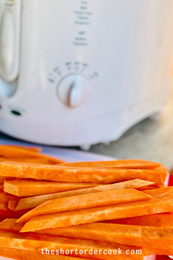 Deep Fried Sweet Potato Fries raw and cut into shoestrings piled up next to a deep fry preheating