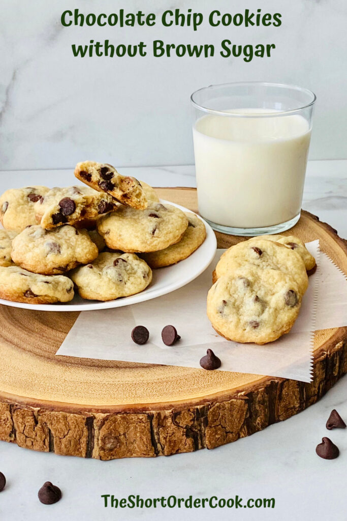 Chocolate Chip Cookies without Brown Sugar PN1 a wood slab with a plate of cookies stacked on top and a few cookies to the side and a glass of milk