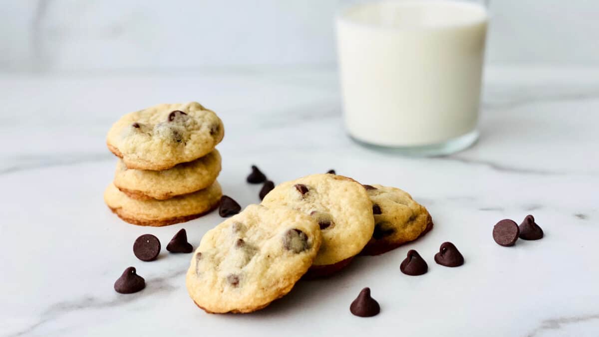 Chocolate Chip Cookies without Brown Sugar featured stack of 3 cookies and in the middle 3 fanned out cookeis with random chocolate chips sprinkles on the counter and a glass of milk