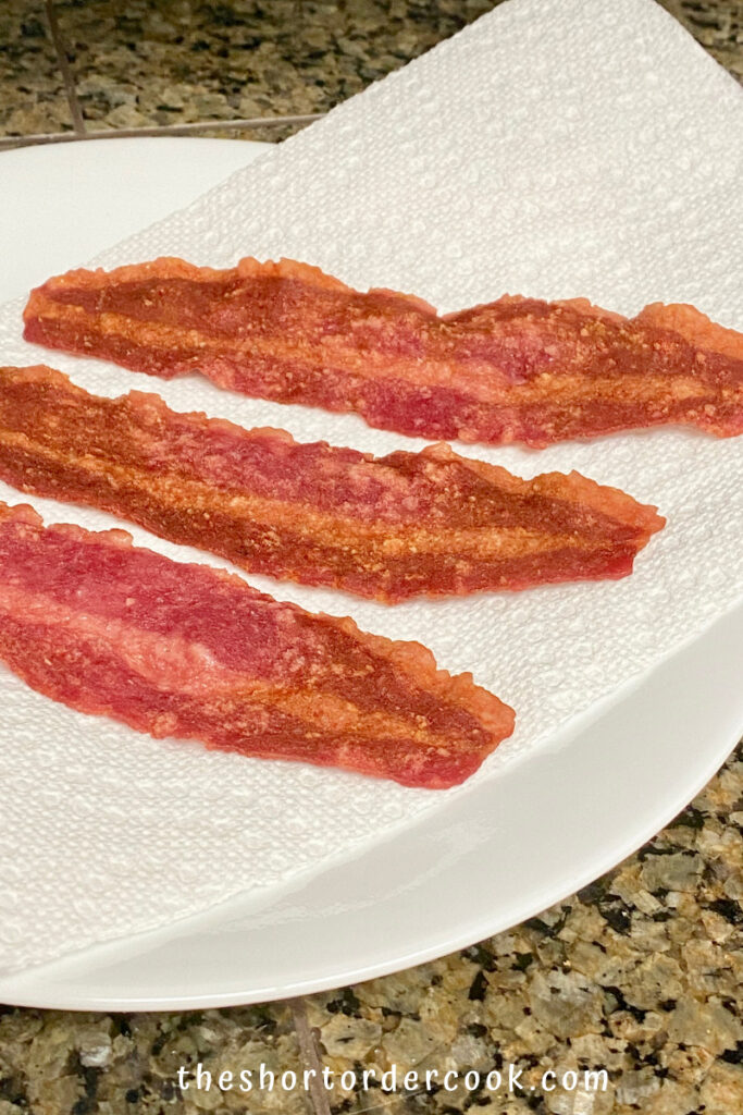 How to Cook Turkey Bacon in the Microwave Oven 3 cooked strips on a plate with paper towels