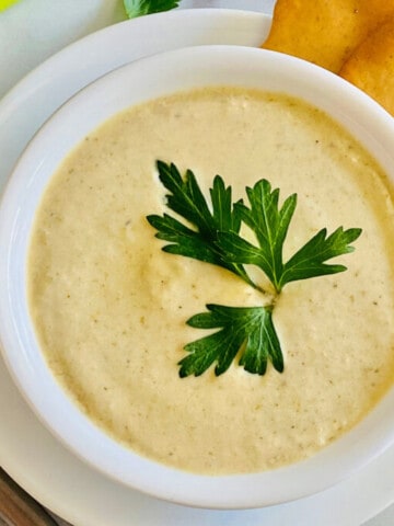 Instant Pot Cream of Celery Soup featured overhead of bowl of soup ready to eat with celery stalks in top left corner and a spoon to the left with crackers on the right top corner