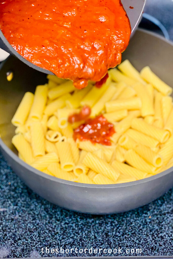 Pasta al Forno (Baked Pasta) pouring sauce over the cooked rigatoni