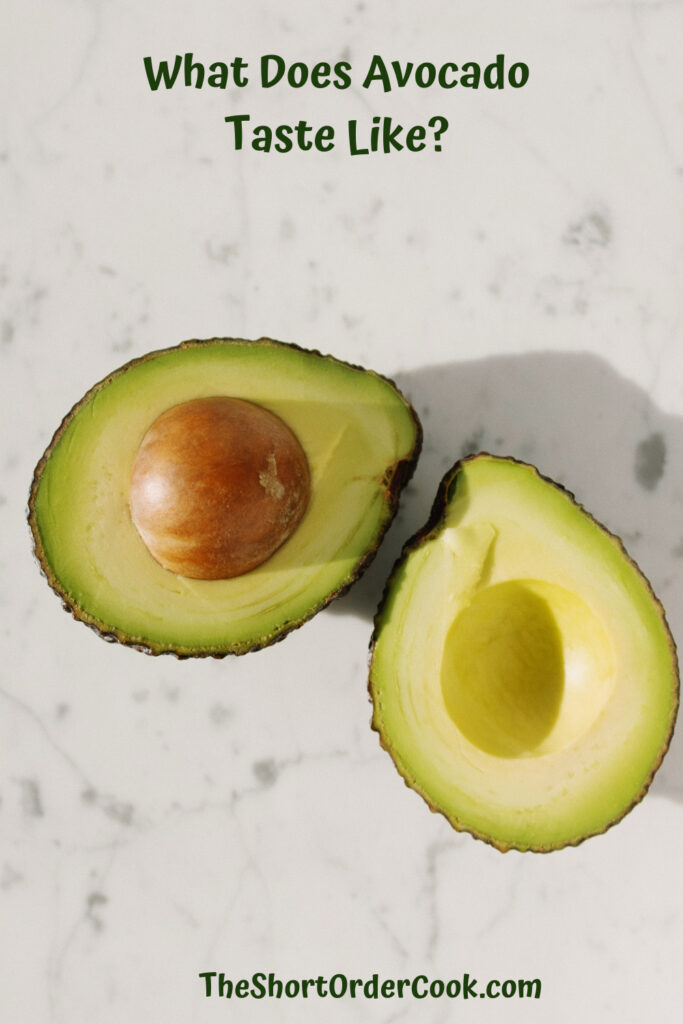 What Does Avocado Taste Like? PN1 an avocado cut in half exposing the pit and flesh sitting on a white countertop