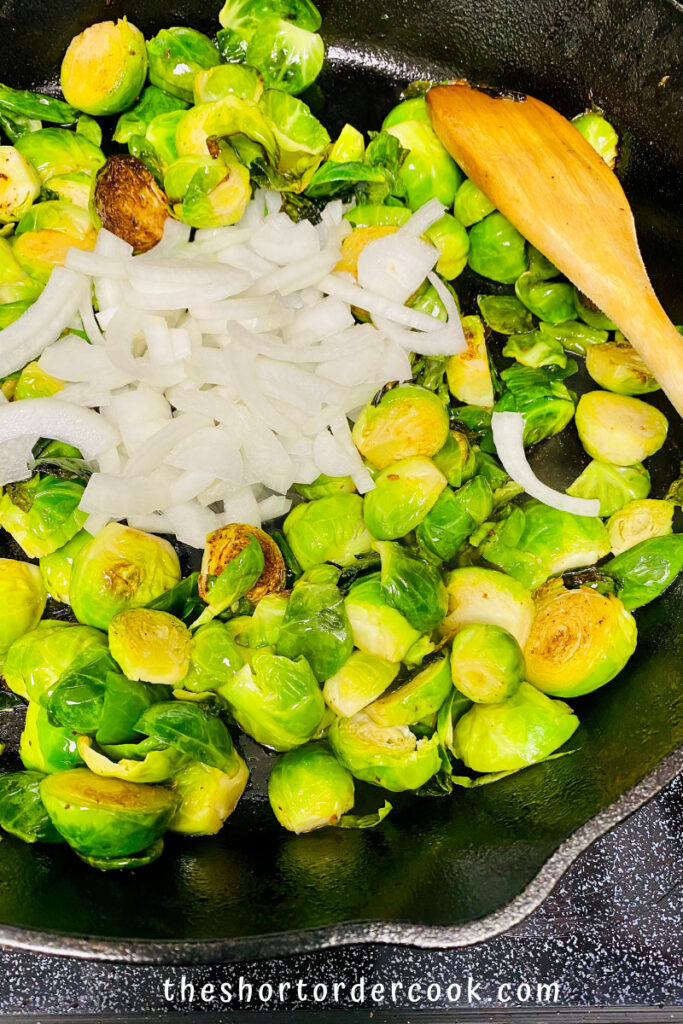 Caramelized Brussel Sprouts with Brown Sugar, Bacon, & Blue Cheese cooked in the pan with raw onions added