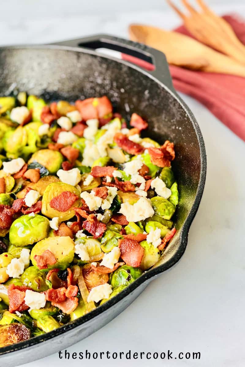Caramelized Brussel Sprouts with Brown Sugar, Bacon, & Blue Cheese ready to eat in the pan with serving spoon and napkin