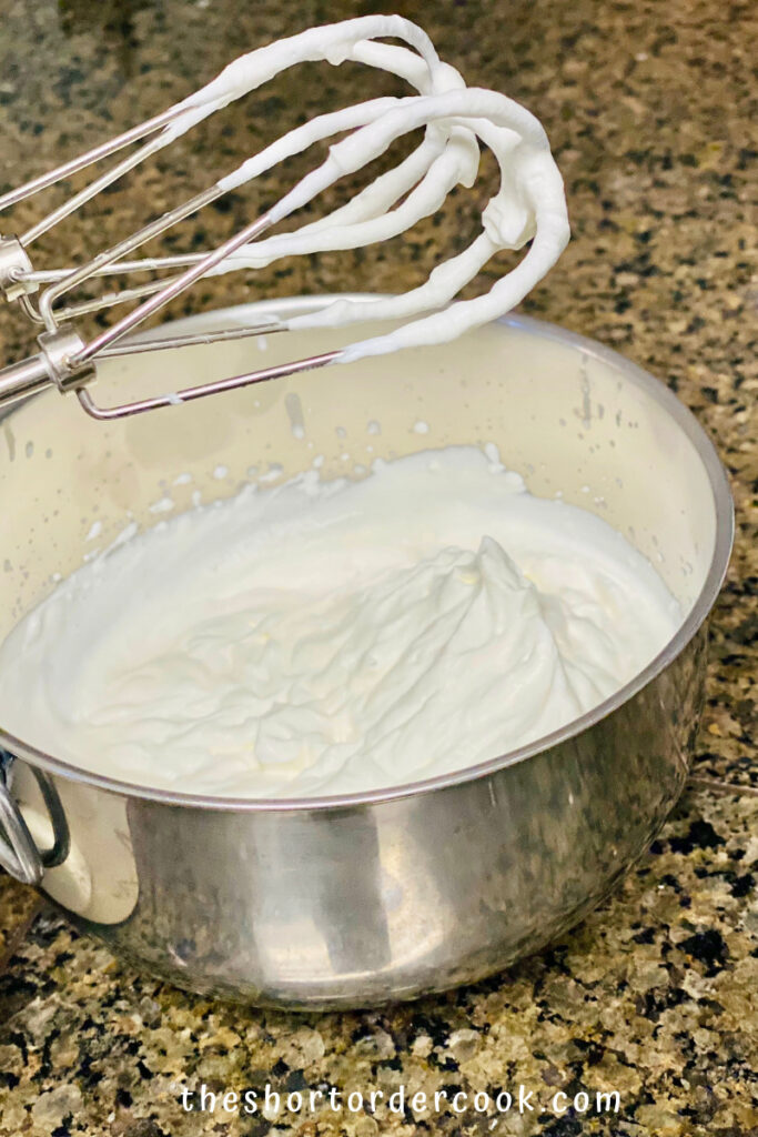 Keto No-Bake Cheesecake cream whipped into stiff peaks in a chilled metal bowl