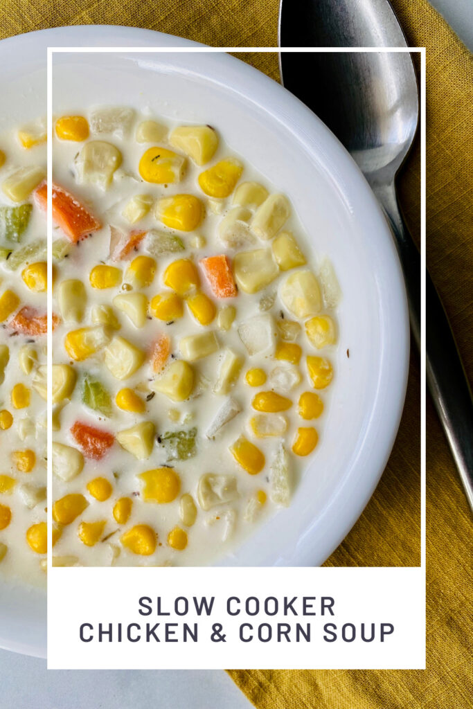 Slow Cooker Chicken & Corn Soup PIN REDO close up overhead image of the bowl ready to eat with corn carrots and more plus a spoon on the side