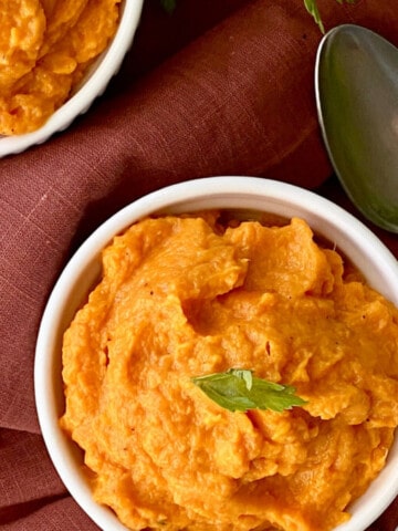 Whipped Sweet Potatoes featured two ramekins full of sweet potatoes with a red napkin spoon and fresh parsley on the table