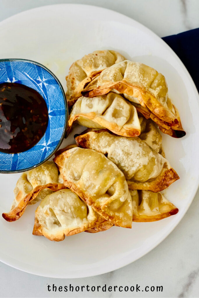 Air Fryer Frozen Potstickers plated and ready to eat with soy dipping sauce and blue napkin
