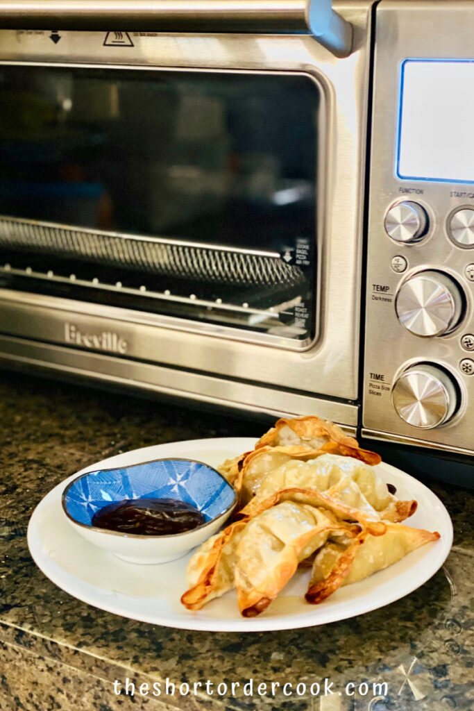 Air Fryer Frozen Potstickers plated in front of the air fryer