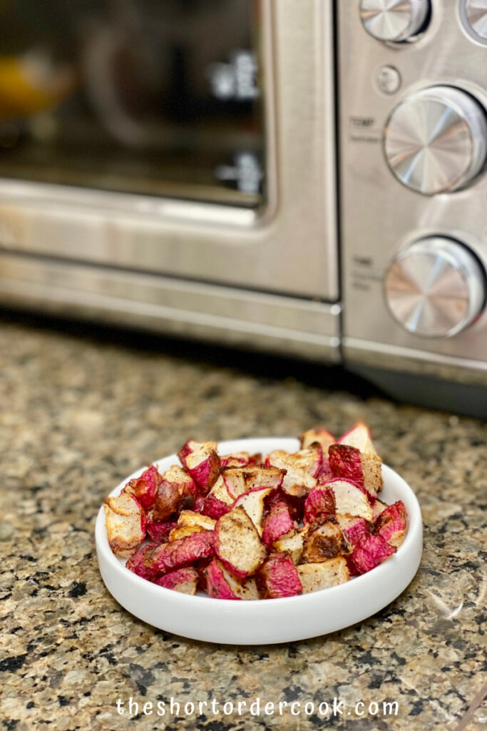 Crispy Air Fryer Keto Radishes plated ready to eat on the counter in front of the air fryer toaster oven
