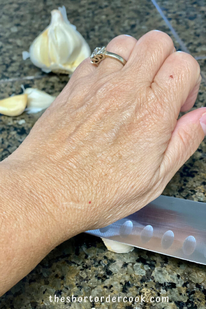 Fried Spaghetti with Eggs smashing a garlic clove with flat side of a chefs knife