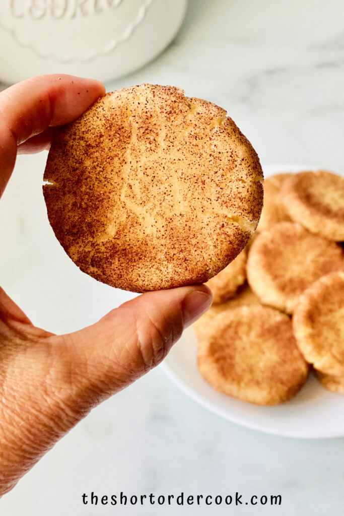 Snickerdoodles without Cream of Tartar hand holding a cookie close up to show the cracked cinnamon tops