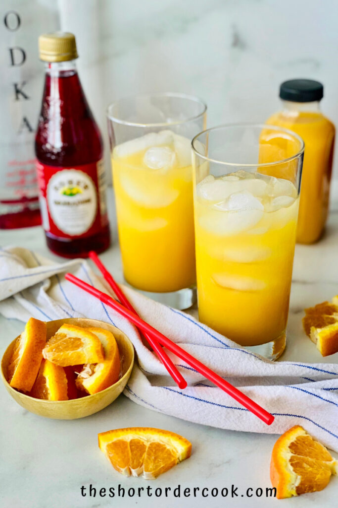 Vodka Sunrise two glasses with ice and orange juice and other ingredients and straws on the counter