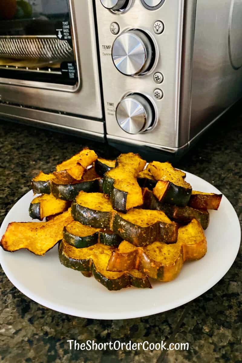Air Fryer Curried Acorn Squash Slices plated in front of the air fryer