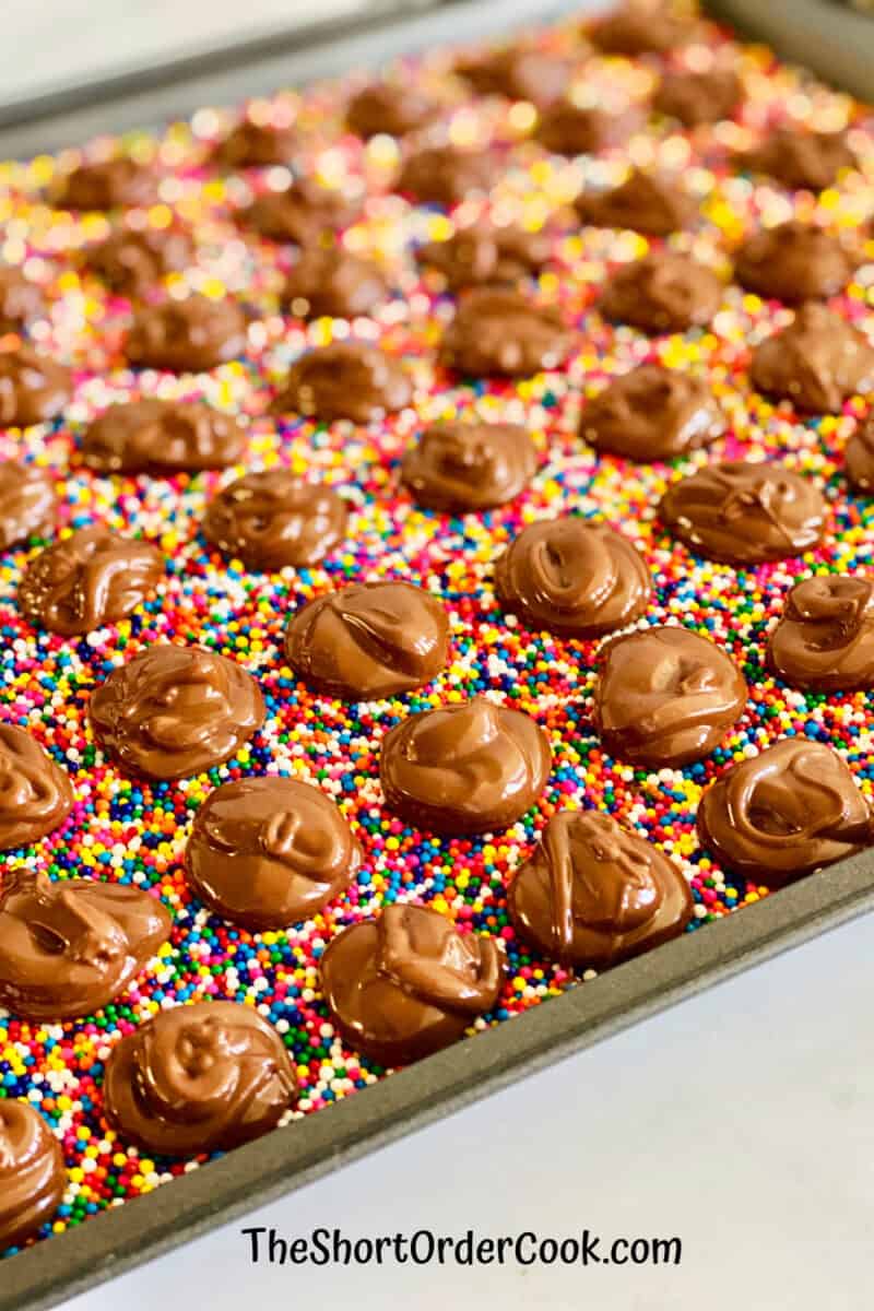 Chocolate Nonpareils Candy full baking sheet covered in nonpareils with chocolate dollops cooling