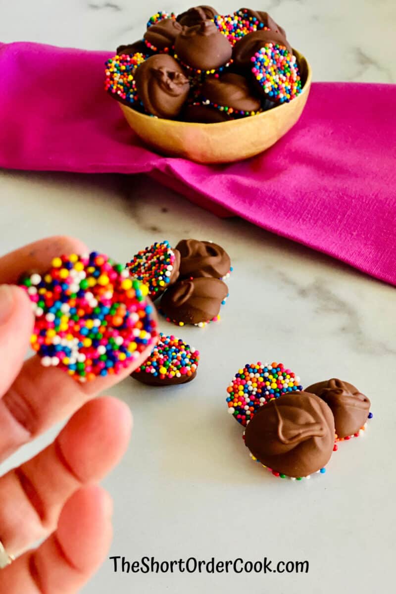 Chocolate Nonpareils Candy ready to eat with a hand holding one