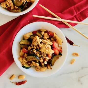 Keto Kung Pao Chicken recipe card with red napkin and two bowls ready to eat with chopsticks