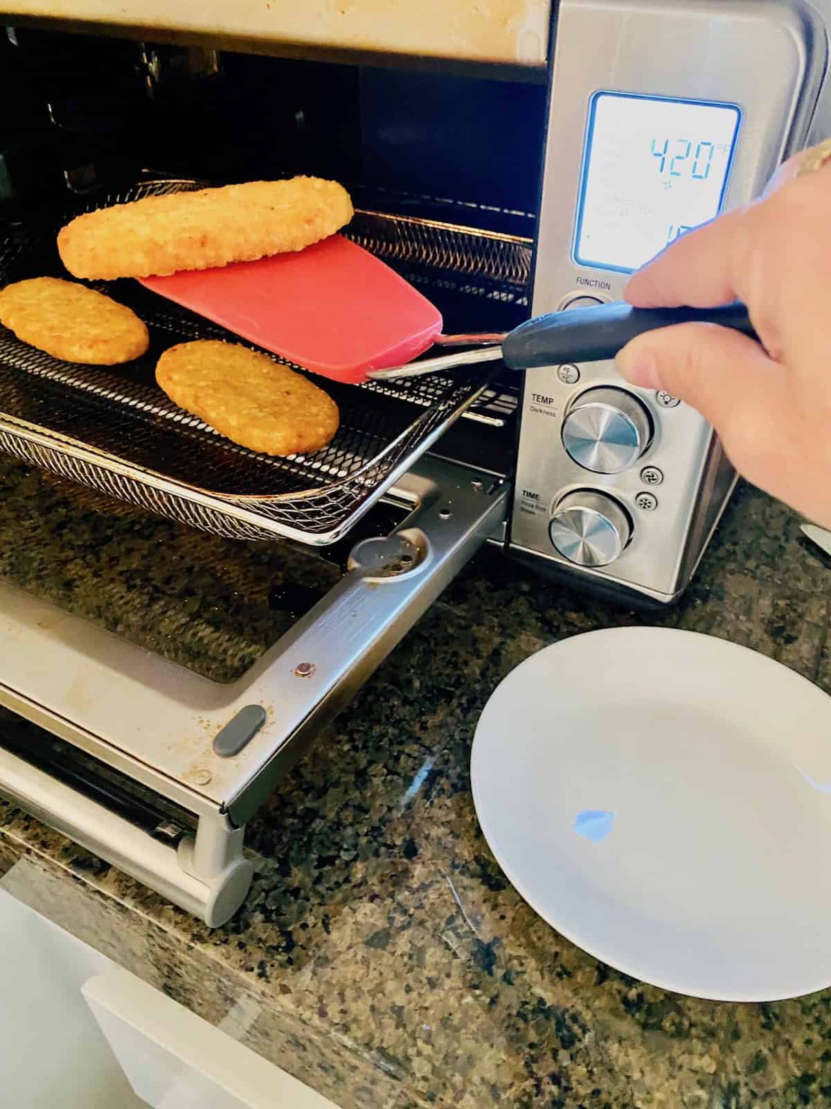 cooked on the air fryer tray with spatula removing one of the air fried hashbrowns