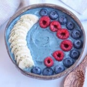 blue smoothie bowl with sliced bananas and berries
