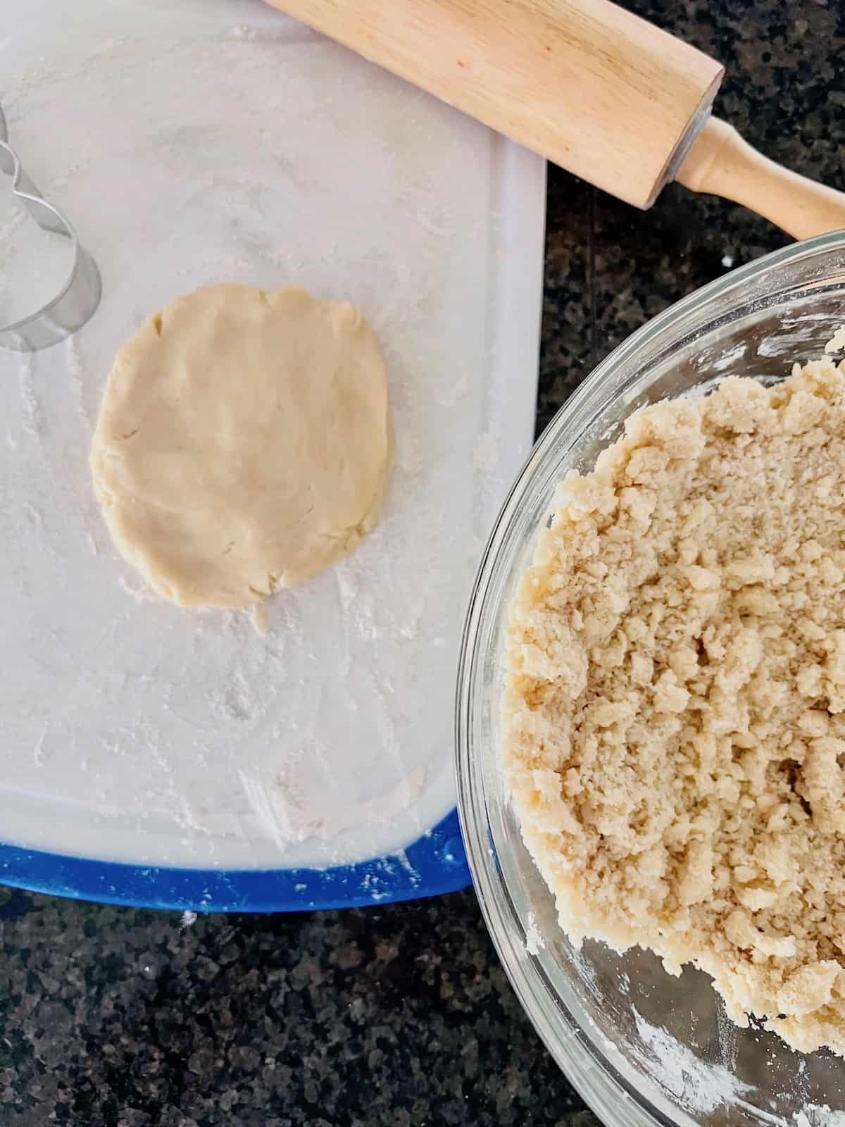Dough that looks crumbly in a bowl next to smooth flat dough on a cutting board.