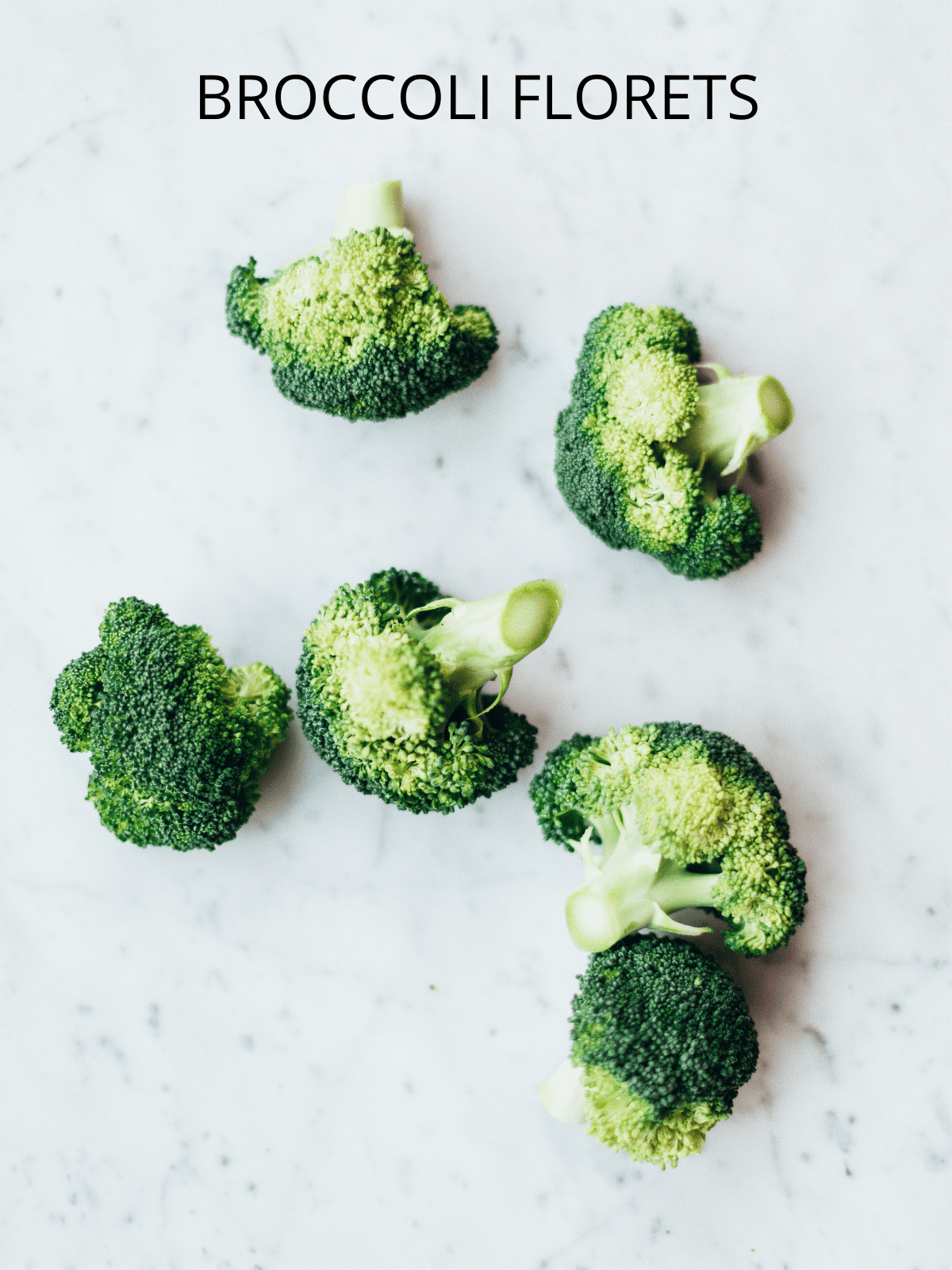 Several broccoli florets on a counter.