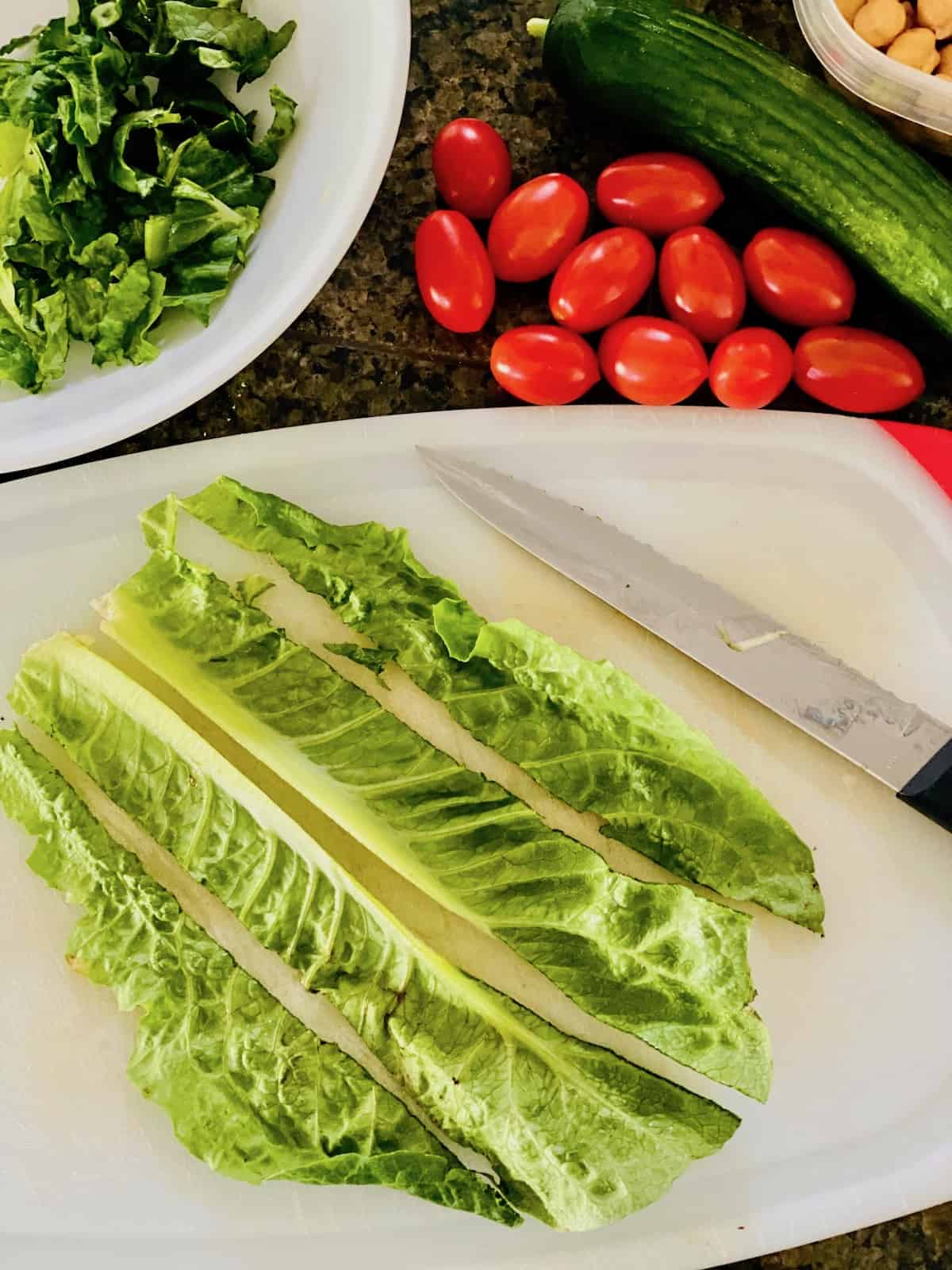 Cutting board with romaine leaves sliced into strips ready to chop