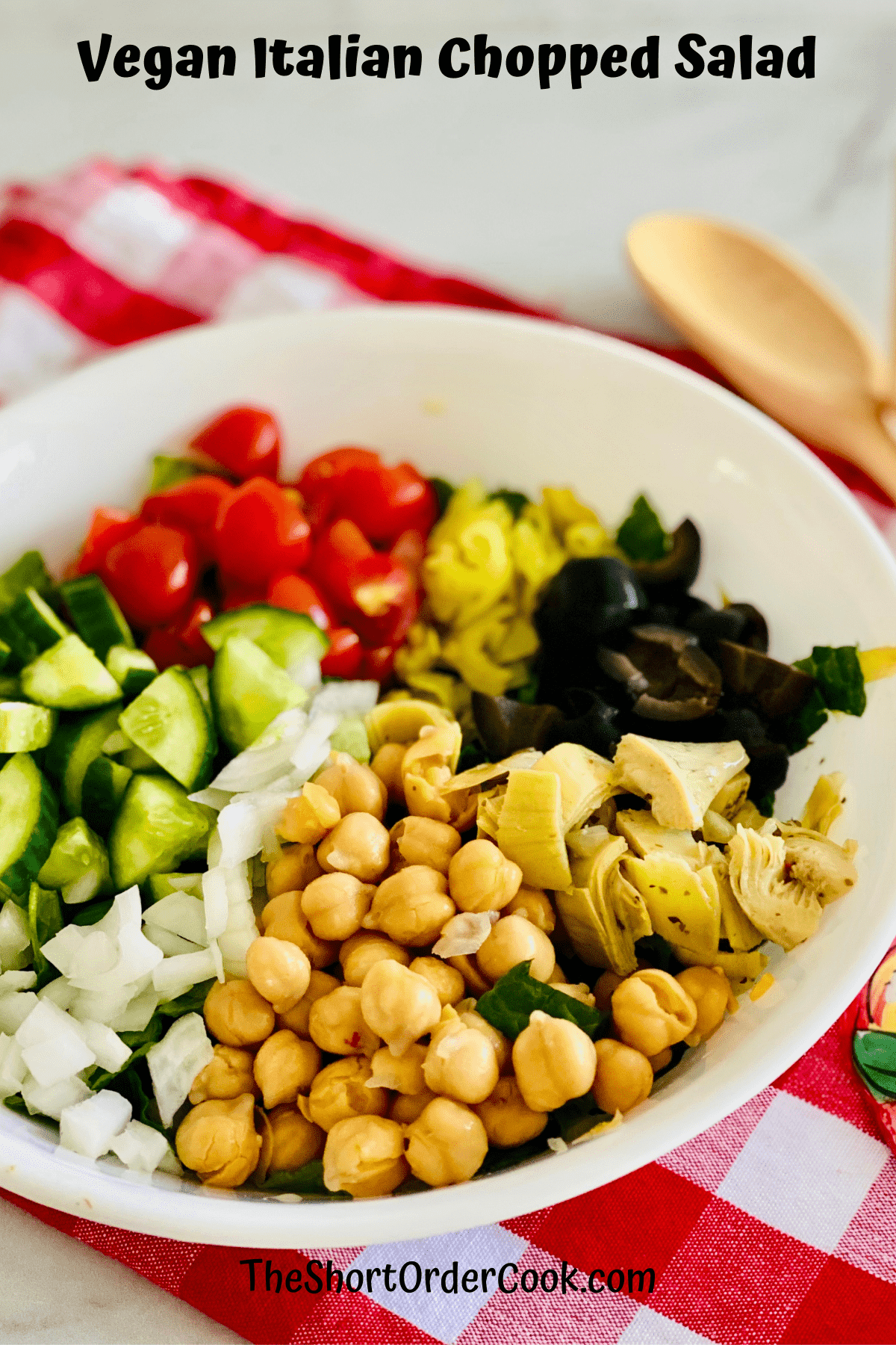 Large bowl of salad with beans, tomatoes, olives, and more on top.