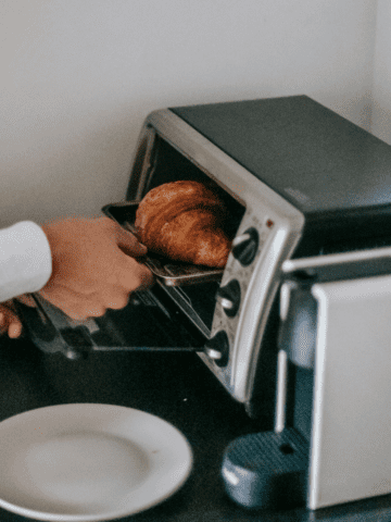Small toaster oven with a croissant being put into it.