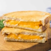 A cut grilled cheese sandwich on a cutting board.